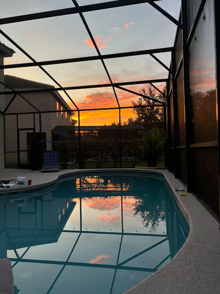 Villa pool at golden hour through the screened lanai
